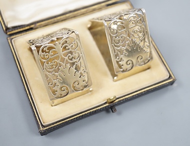 A late Victorian cased pair of pierced silver triangular napkin rings, by Goldsmiths & Silversmiths Co Ltd, London, 1900, with engraved inscription.